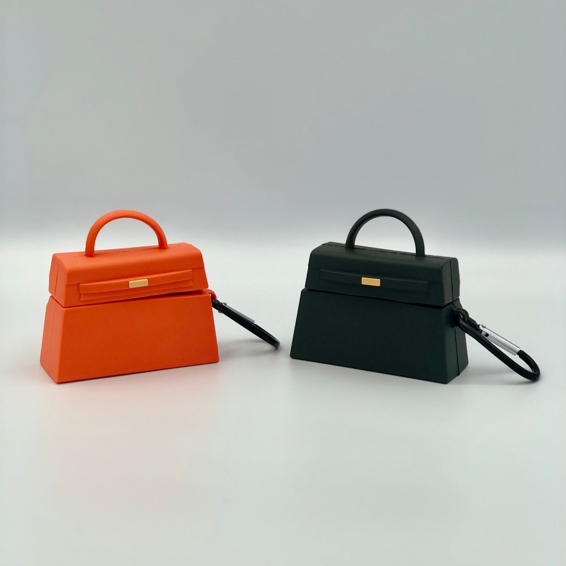 One orange and one black handbag shaped silicone airpod case with grey background