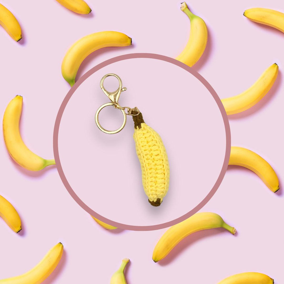 Banana-shaped crochet handbag charm on a pink background with banana pattern