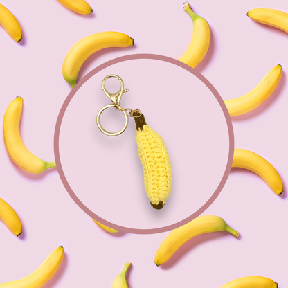 Banana-shaped crochet handbag charm on a pink background with banana pattern