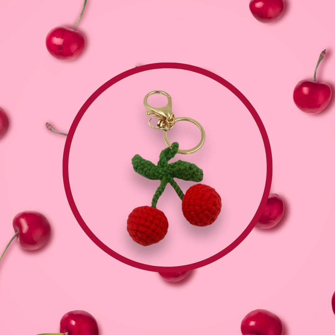 Cherry-shaped crochet handbag charm on a pink background with cherry pattern