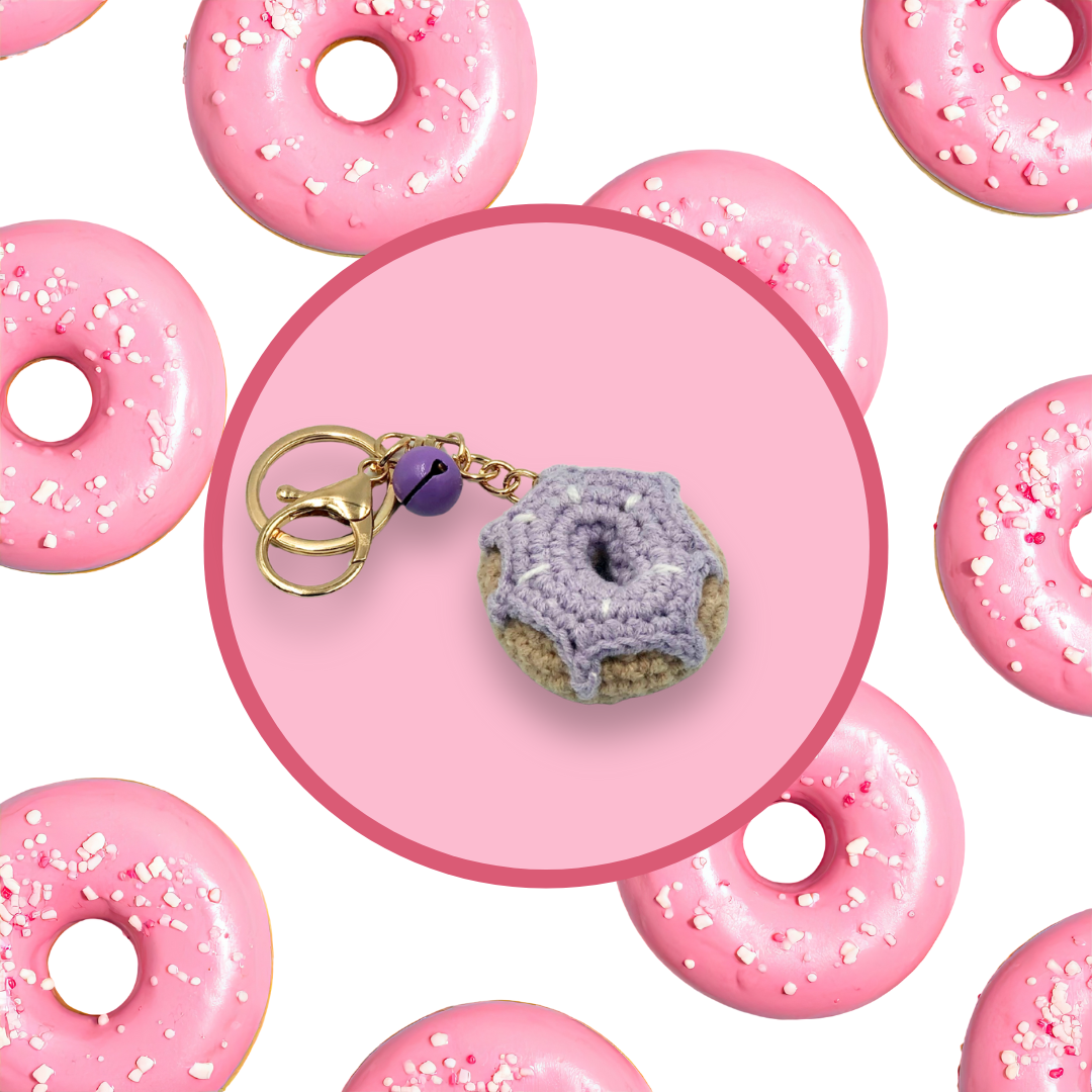 Purple donut-shaped crochet handbag charm on a pink background with donut pattern