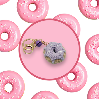 Purple donut-shaped crochet handbag charm on a pink background with donut pattern