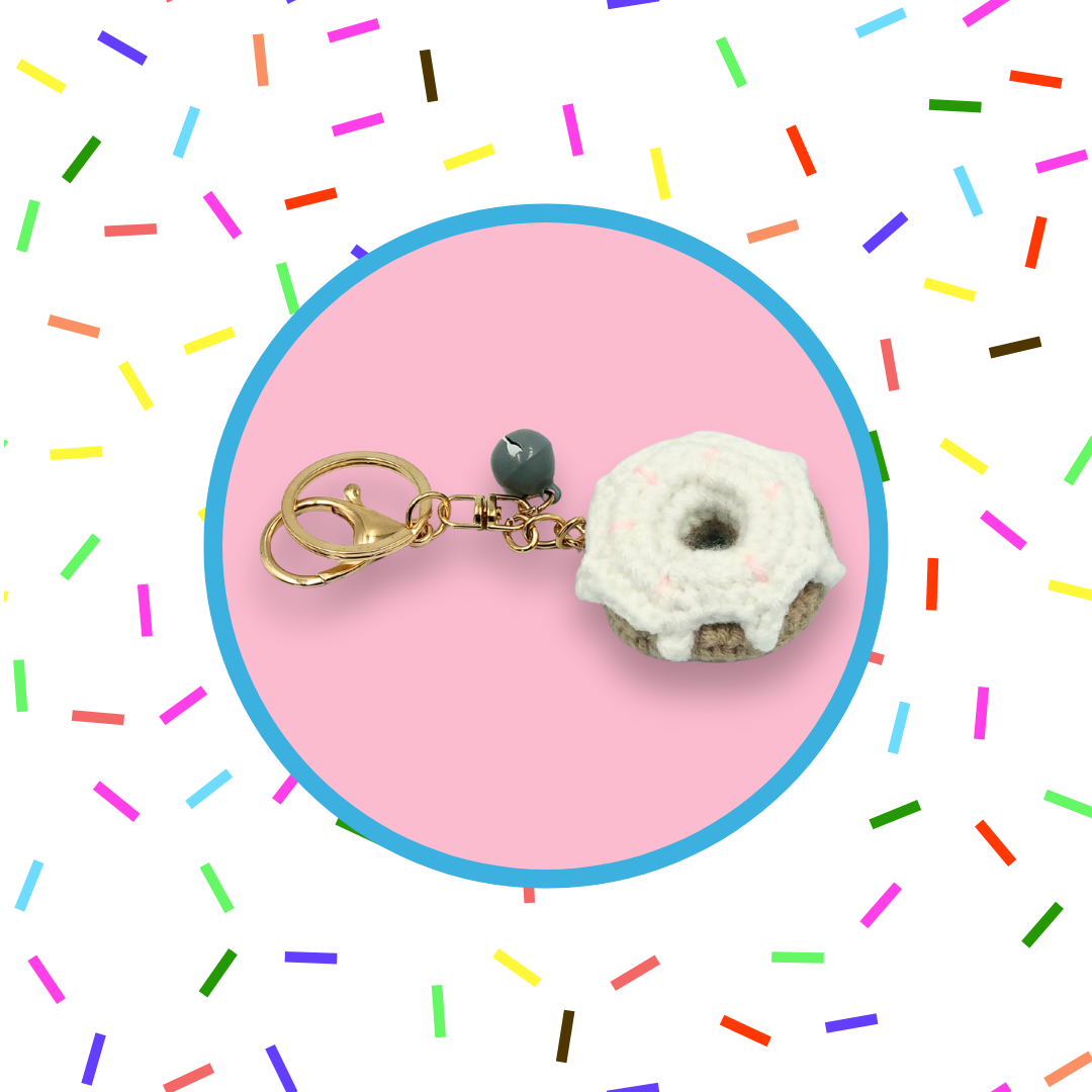 White donut-shaped crochet handbag charm on a pink background with sprinkles pattern