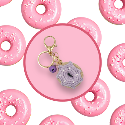 Purple donut-shaped crochet handbag charm on a pink background with donut pattern