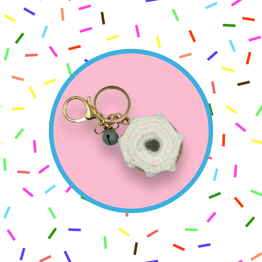 White donut-shaped crochet handbag charm on a pink background with sprinkles pattern